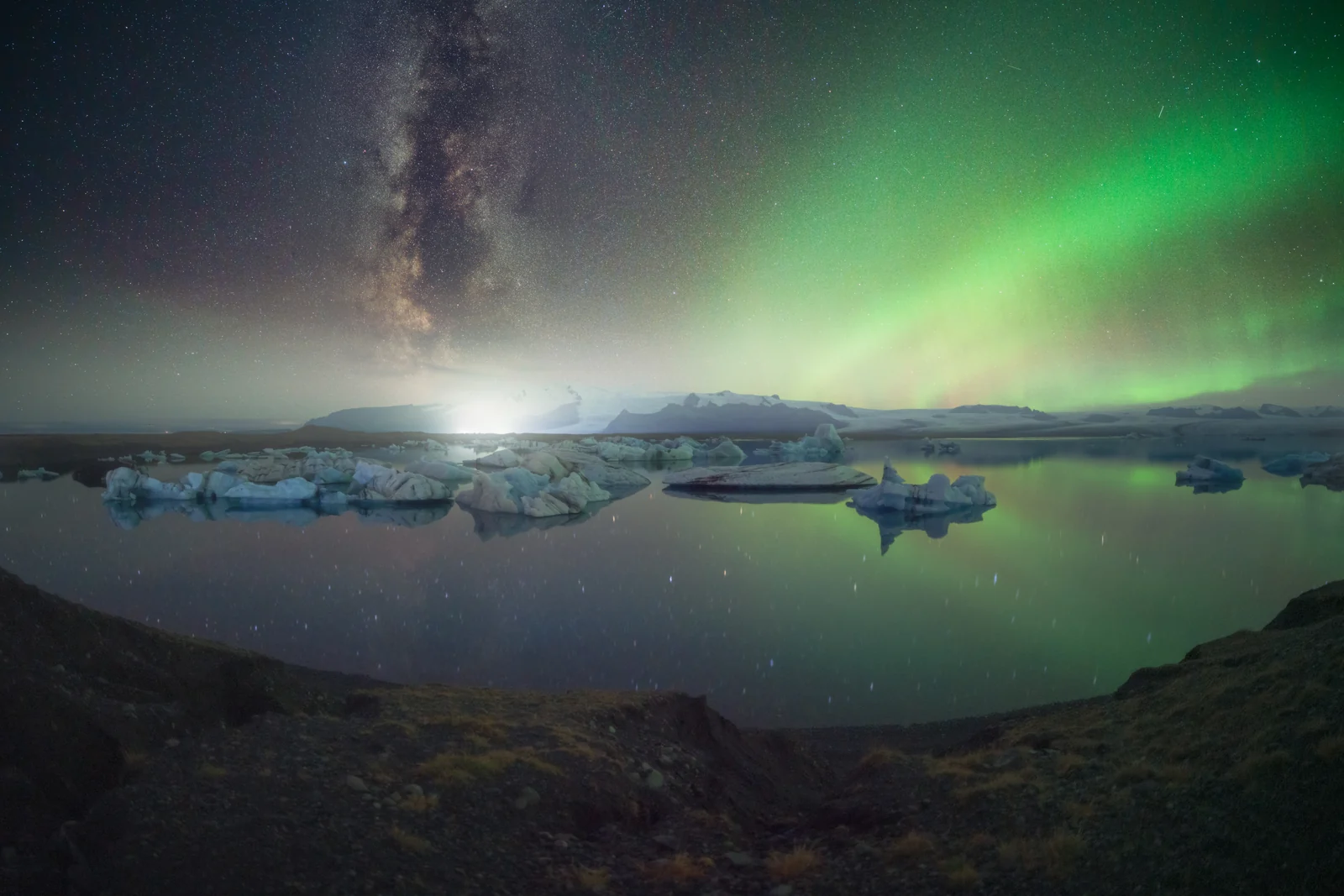 Aurora e Via Lattea sopra una laguna con ghiaccio galleggiante