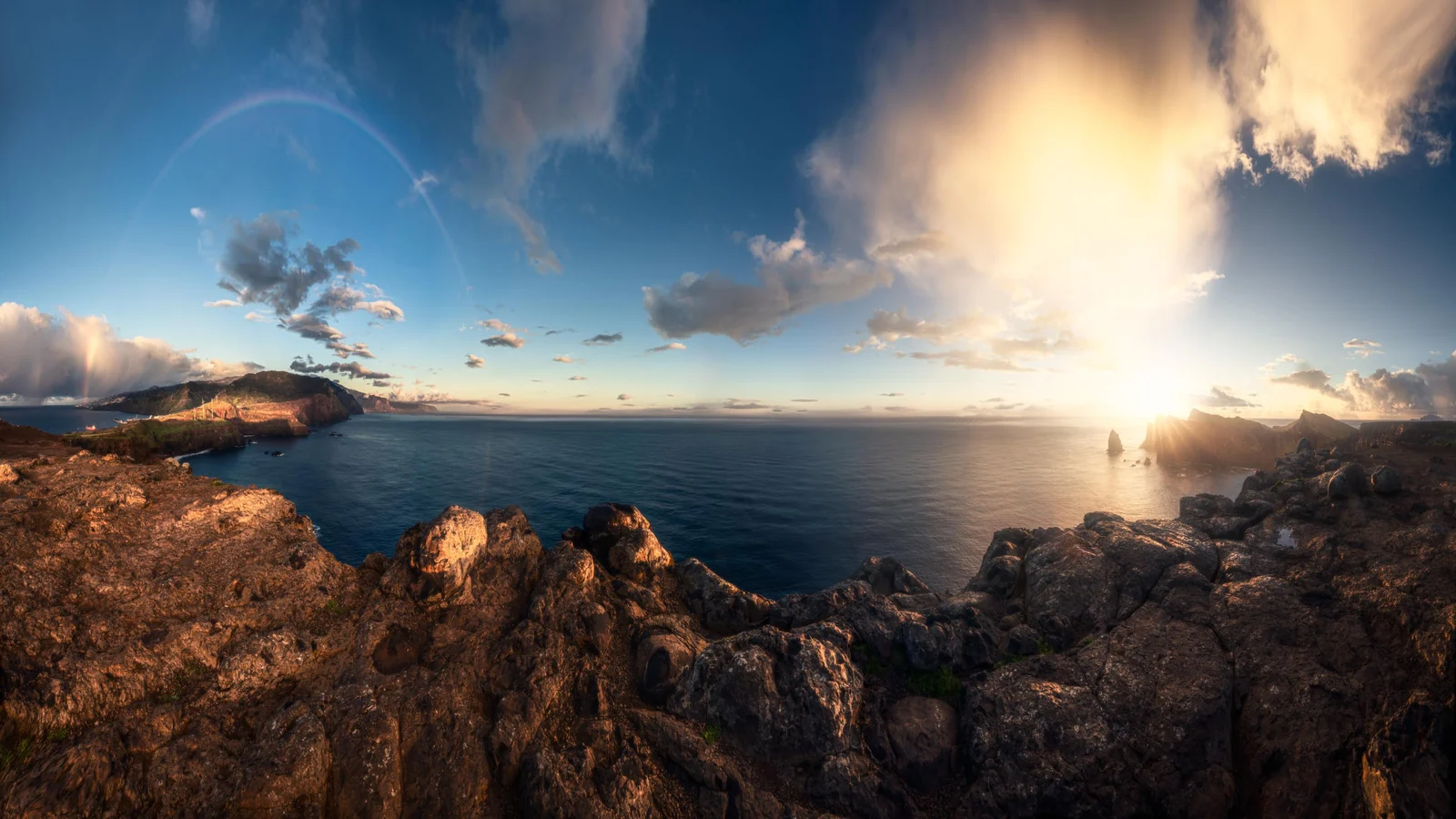Costa rocciosa e mare nella luce bassa del sole tra le nuvole