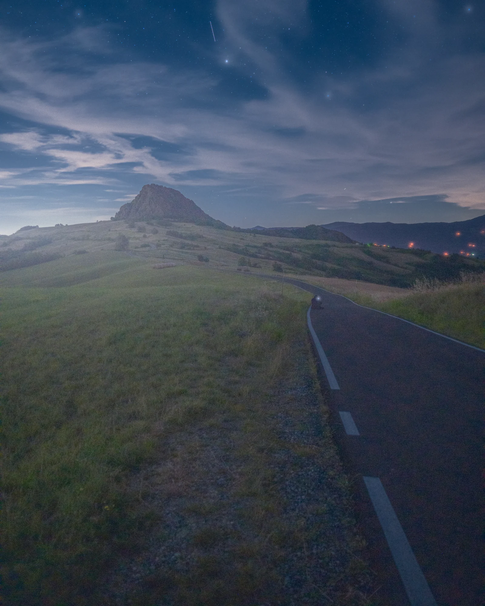 Strada tra le colline verso una montagna sotto un cielo blu